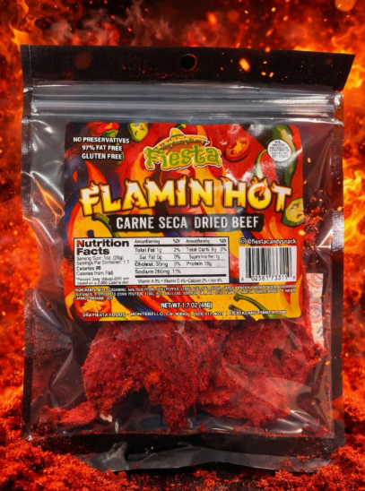 A clear plastic bag of Fiesta Flamin' Hot Carne Seca Dried Beef seasoning, showing the bright red seasoning inside, set against a fiery orange and red background.